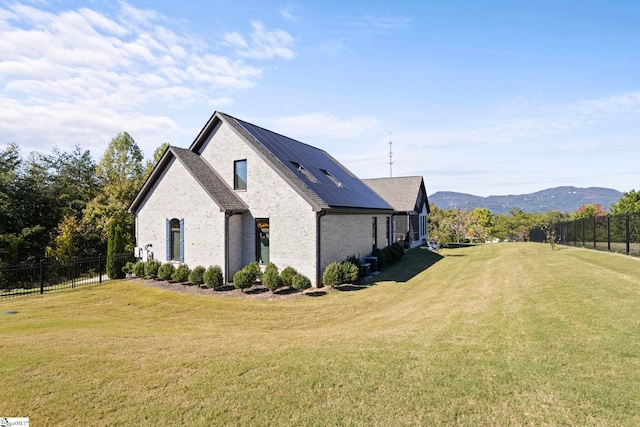 view of home's exterior featuring brick siding, fence, a mountain view, and a yard