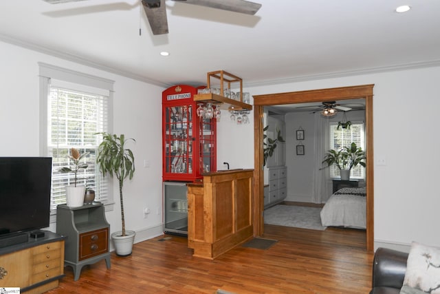 interior space featuring crown molding, visible vents, ceiling fan, a bar, and wood finished floors