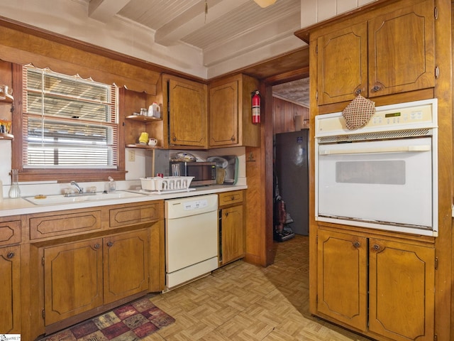 kitchen with brown cabinets, open shelves, light countertops, a sink, and white appliances