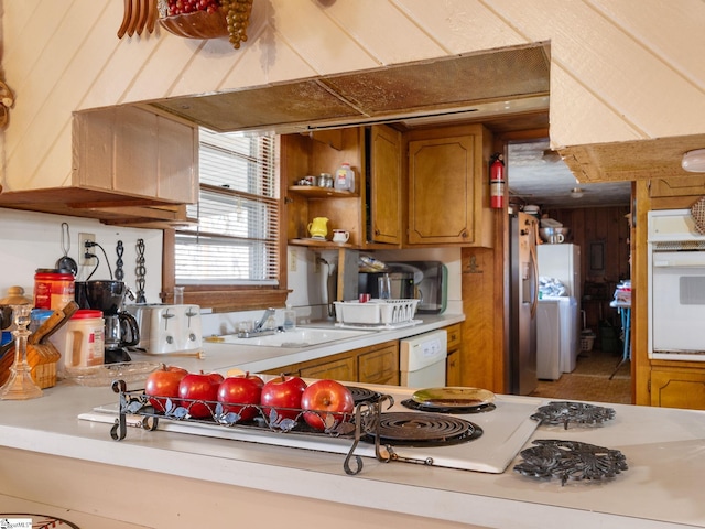 kitchen with a sink, white appliances, brown cabinetry, and light countertops