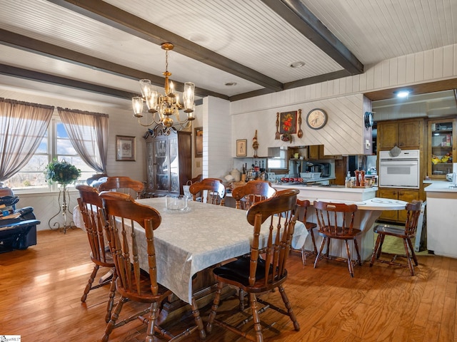 dining area with light wood-type flooring, a chandelier, and beam ceiling