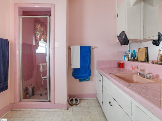 full bathroom with a shower stall, baseboards, tile patterned flooring, and vanity