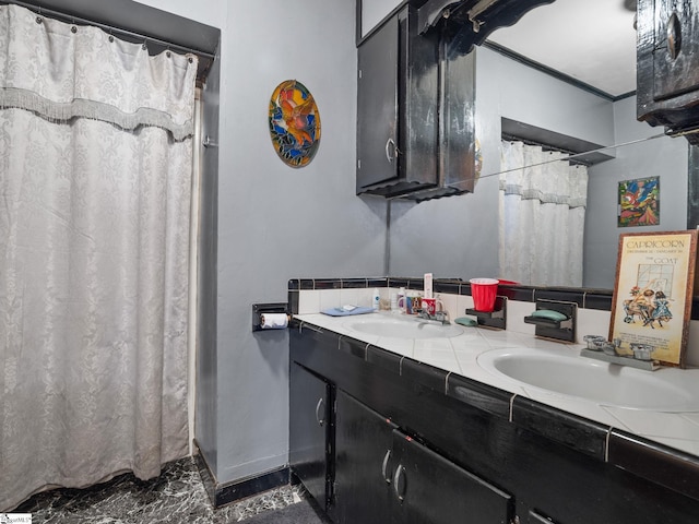 bathroom with marble finish floor, double vanity, a sink, and crown molding