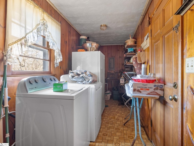 washroom with wood walls, laundry area, washer and clothes dryer, and a textured ceiling