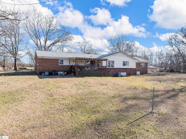 back of house with a wooden deck, metal roof, a lawn, and brick siding