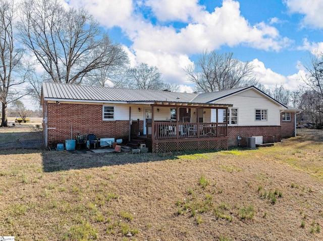 rear view of house with metal roof, brick siding, a yard, and central air condition unit