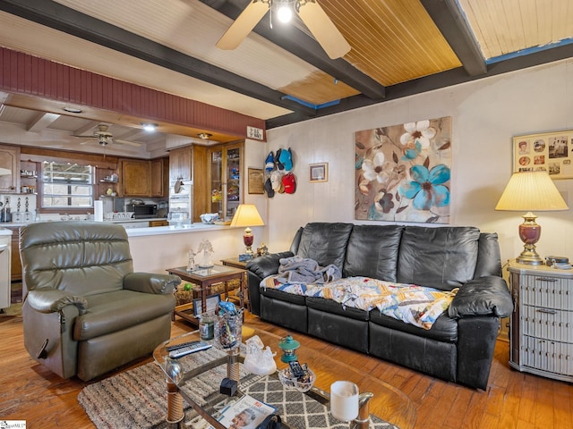 living room with ceiling fan, beamed ceiling, and hardwood / wood-style floors