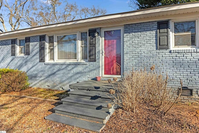 entrance to property with crawl space and brick siding