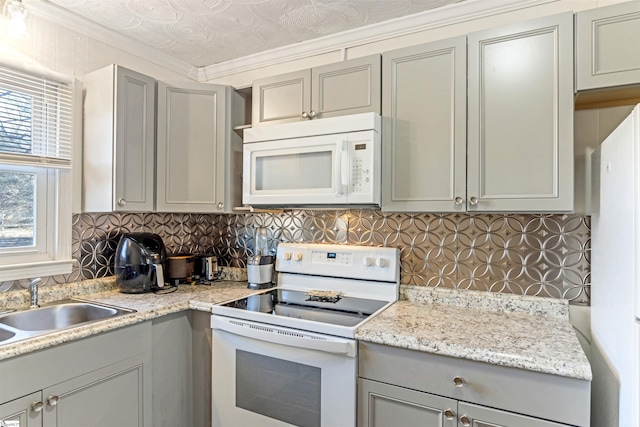 kitchen with white appliances, decorative backsplash, gray cabinets, crown molding, and a sink