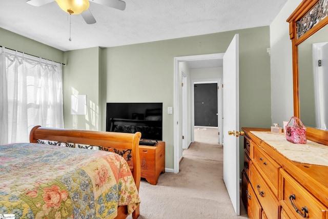 bedroom featuring light carpet, ceiling fan, a textured ceiling, and baseboards