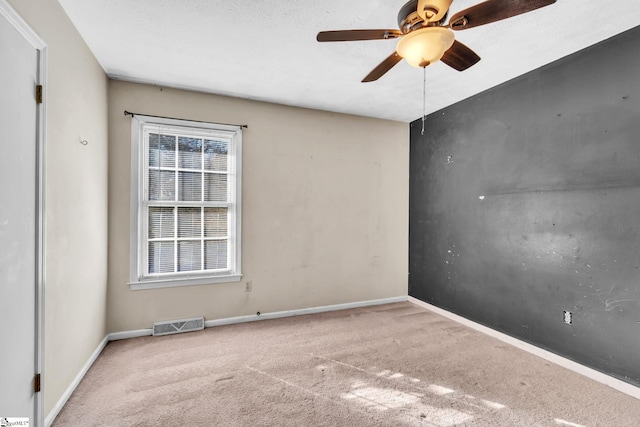 carpeted empty room featuring ceiling fan, visible vents, and baseboards