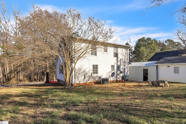 rear view of house with central air condition unit and a yard