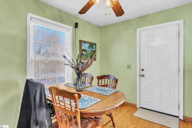 dining room featuring light wood finished floors, a ceiling fan, and baseboards