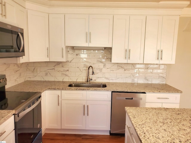 kitchen featuring light stone counters, appliances with stainless steel finishes, white cabinets, and a sink