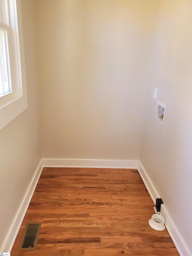 unfurnished room featuring visible vents, baseboards, and wood finished floors