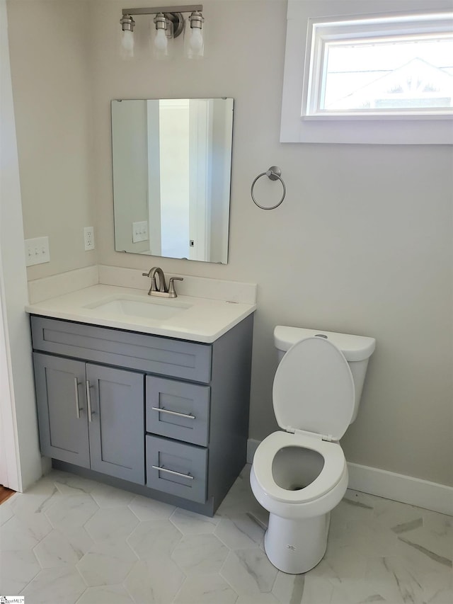 bathroom featuring toilet, marble finish floor, and vanity