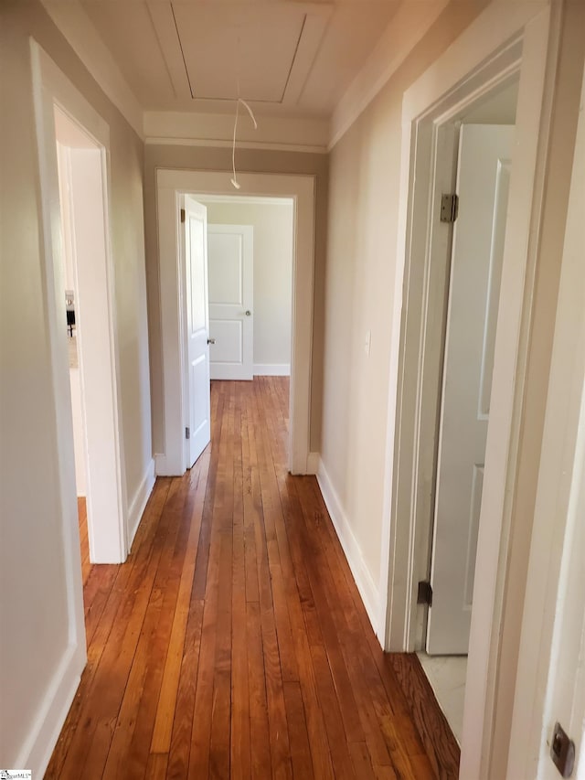 hall featuring dark wood-style floors, attic access, and baseboards