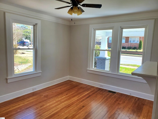 spare room with visible vents, hardwood / wood-style floors, ornamental molding, a ceiling fan, and baseboards