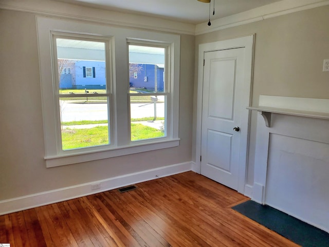 spare room with hardwood / wood-style flooring, visible vents, and baseboards