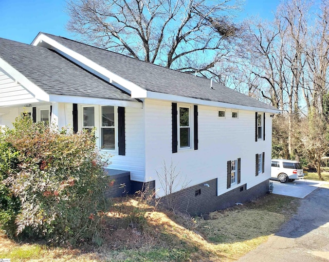 view of home's exterior with roof with shingles and crawl space