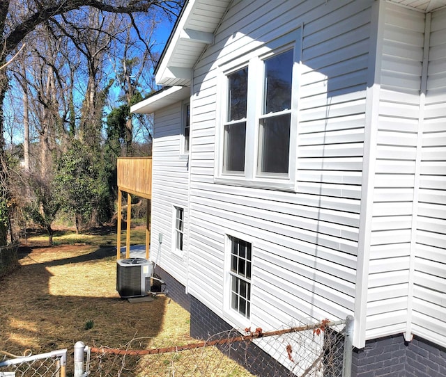 view of side of home with central AC unit and a yard