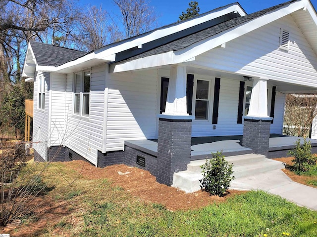 view of side of property featuring crawl space, covered porch, and a shingled roof