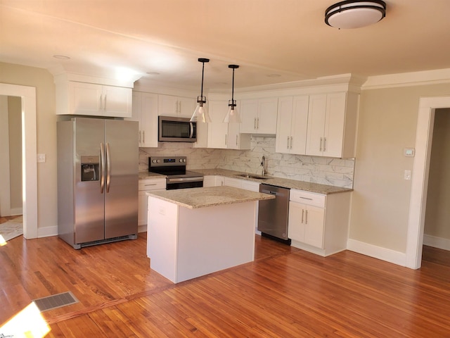 kitchen with tasteful backsplash, stainless steel appliances, a sink, and wood finished floors