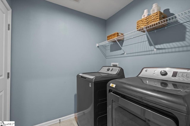 washroom featuring laundry area, washer and clothes dryer, and baseboards