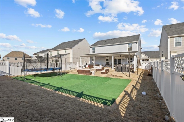 back of property with a fenced backyard, a trampoline, a lawn, and a patio