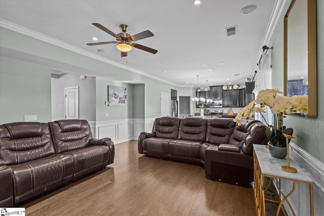 living room with recessed lighting, wood finished floors, visible vents, ornamental molding, and wainscoting