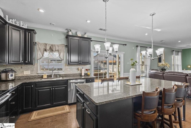 kitchen with dark cabinets, a sink, visible vents, appliances with stainless steel finishes, and a center island