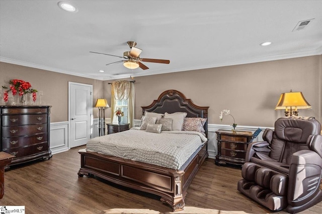 bedroom with visible vents, ornamental molding, wood finished floors, and wainscoting