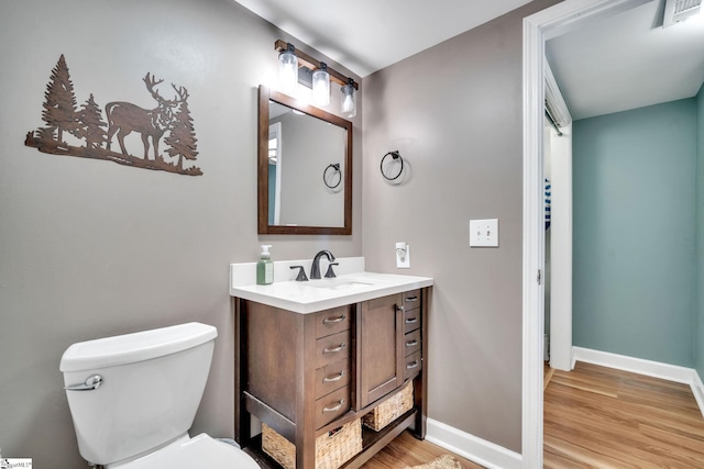 bathroom featuring toilet, wood finished floors, vanity, visible vents, and baseboards