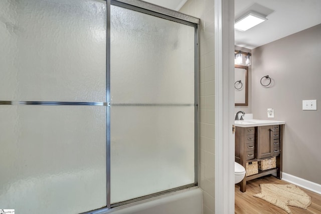 full bathroom featuring bath / shower combo with glass door, toilet, vanity, wood finished floors, and baseboards