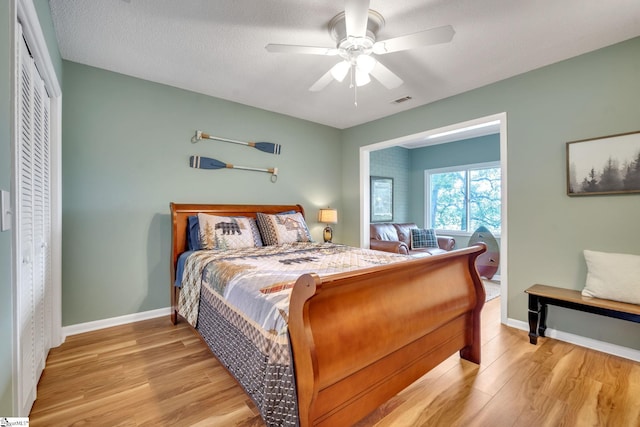 bedroom featuring baseboards, a ceiling fan, visible vents, and light wood-style floors