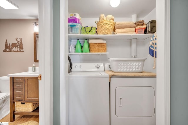 clothes washing area with laundry area, washer and clothes dryer, and wood finished floors