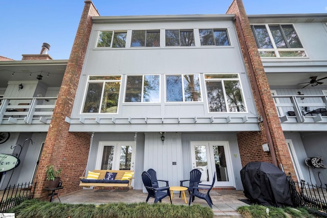 rear view of property featuring french doors, a patio area, brick siding, and a balcony