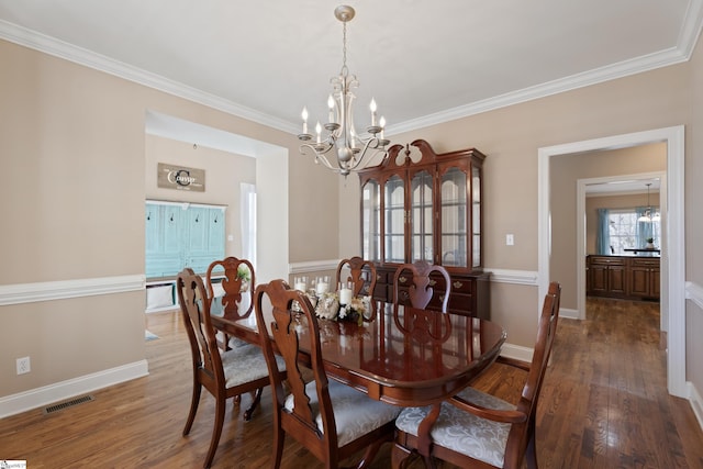 dining area with baseboards, wood finished floors, visible vents, and an inviting chandelier