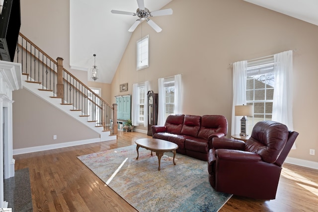 living area with wood finished floors, ceiling fan, baseboards, and stairs