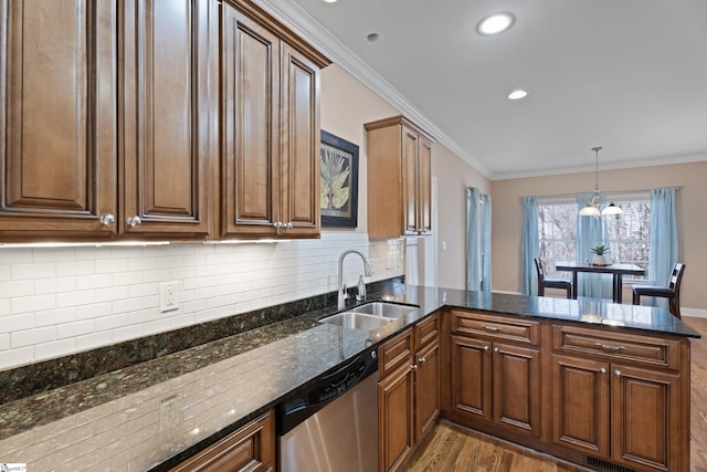 kitchen with a peninsula, wood finished floors, a sink, ornamental molding, and dishwasher