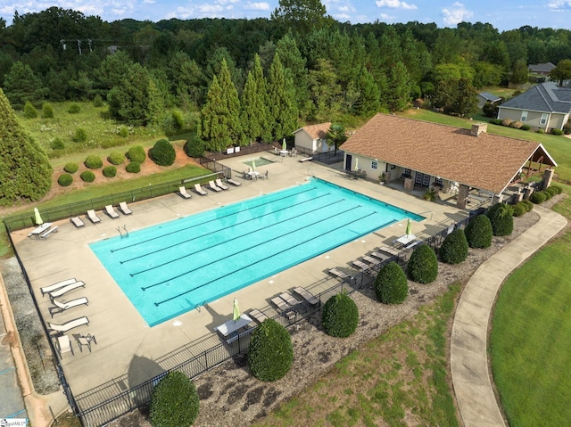 pool featuring fence, a view of trees, and a patio