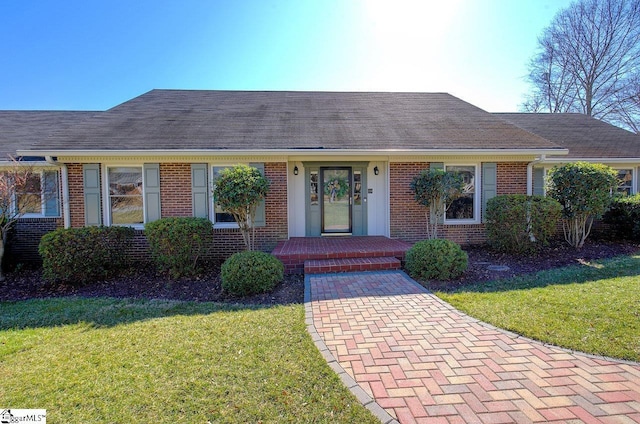 ranch-style home featuring brick siding, a front lawn, and a shingled roof