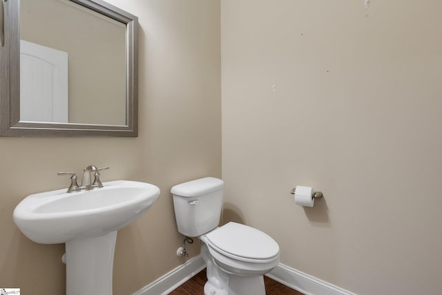 bathroom with wood finished floors, a sink, toilet, and baseboards