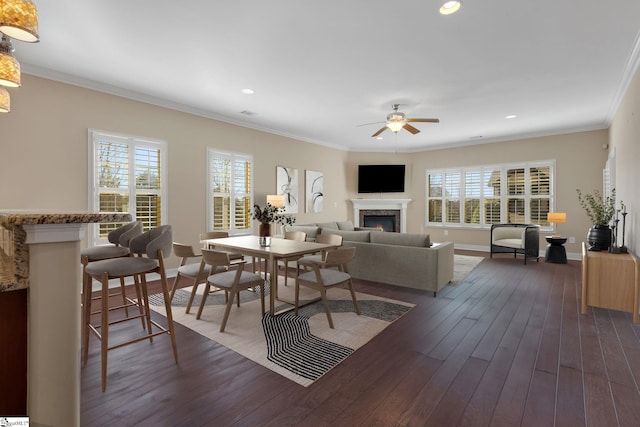 living room with dark wood-style floors, a healthy amount of sunlight, and crown molding