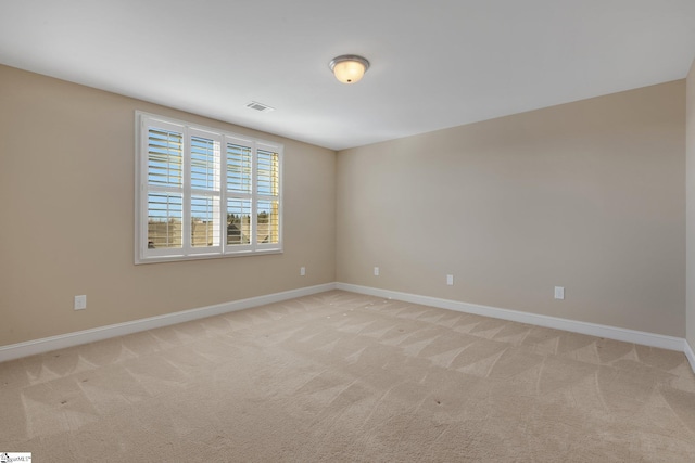 empty room with baseboards, visible vents, and light colored carpet