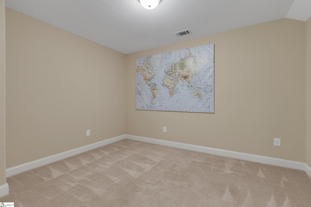 empty room featuring light carpet, vaulted ceiling, visible vents, and baseboards