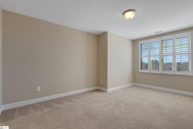 spare room with light colored carpet, visible vents, and baseboards