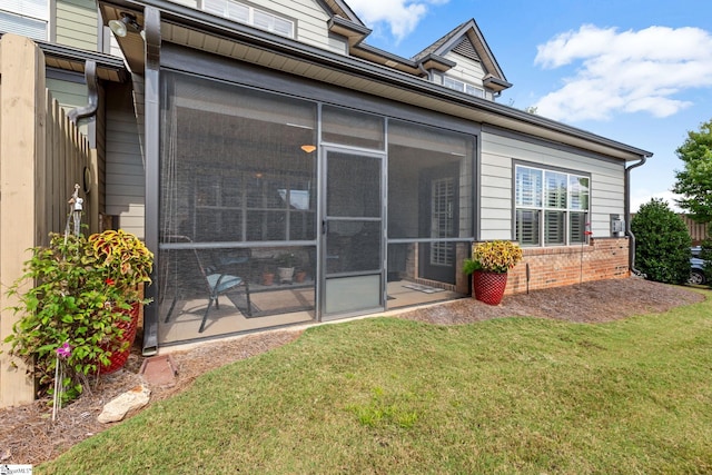 rear view of house featuring a sunroom, a lawn, and brick siding