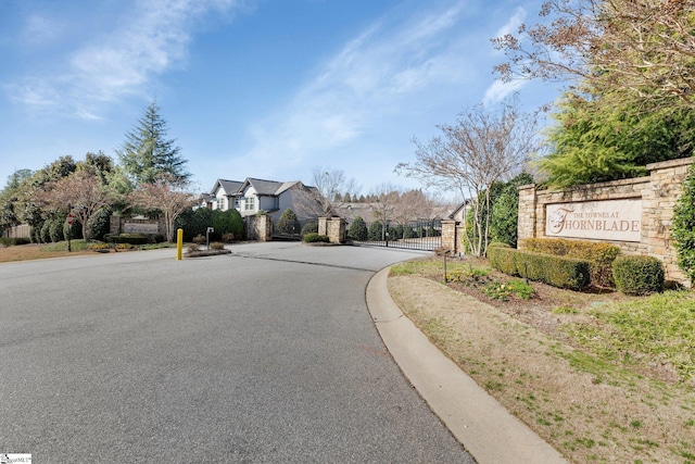 view of street featuring a gate, a gated entry, and curbs