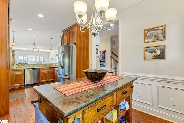 kitchen featuring ornamental molding, appliances with stainless steel finishes, brown cabinetry, and wood-type flooring